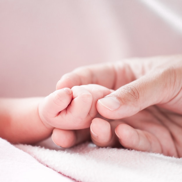 Mother hand holding asian newborn baby girl hand while she sleeping with love