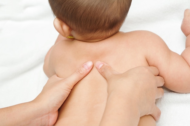 Mother hand massaging back muscle of her baby