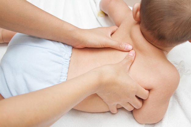 Mother hand massaging back muscle  of her baby