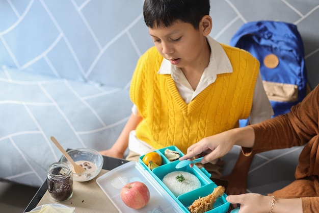 Mother hands giving tasty lunch in box to her son prepare to school