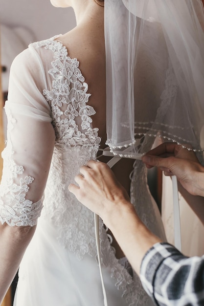 Mother hands holding ribbons and helping dressing beautiful bride in morning bridal getting ready in the morning mom and daughter moments