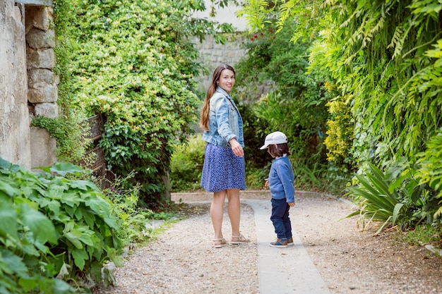 Mother and handsome baby boy walking outdoor in old city park