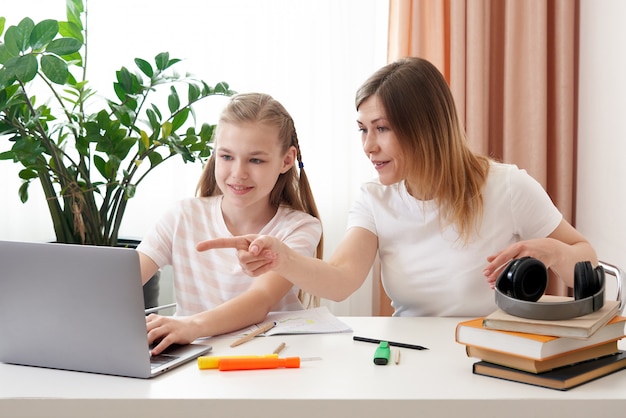 Mother helping daughter to do homework. The concept of home education in quarantine. Fun during distance learning