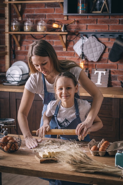 Mother helping to girl with rolling pin