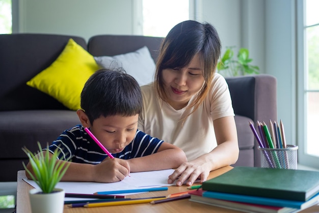 Mother helping son writing homework Cute Asian mother helping your son doing your homework