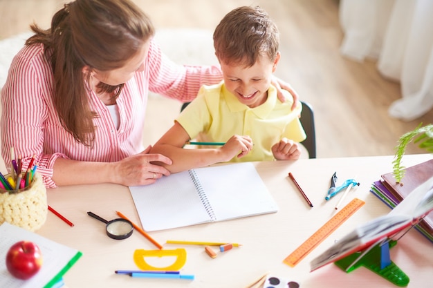 Mother helps son to do lessons. 