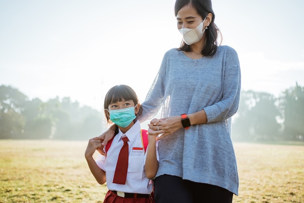 Mother and her daughter walking together and wear face mask