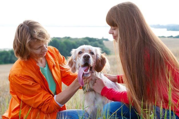 Mother and her daughter with dog Irish setter outdoors