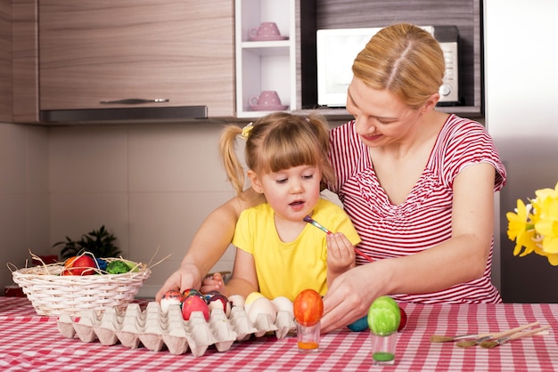 Mother and her little child  painting the easter eggs