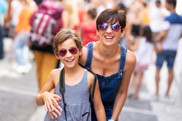 Mother and her little daughter traveling together in urban background.