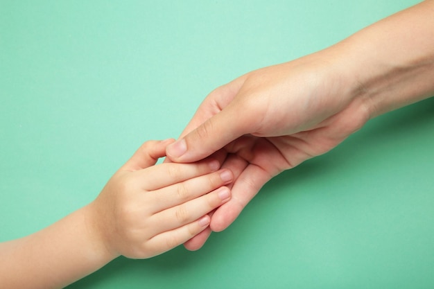 Mother holding daughter hand on mint background