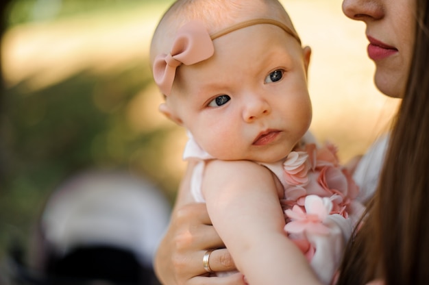 Mother holding her daughter on hands in the public park