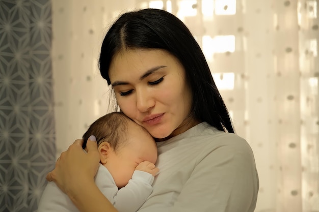 Mother holds a child a baby in her arms the child wants to sleep