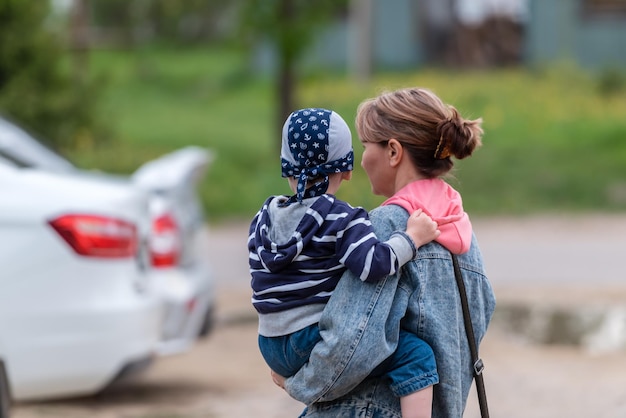 A mother holds a child in her arms a view from the back