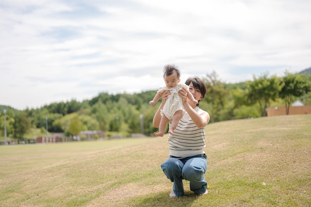 A mother holds her baby in a field