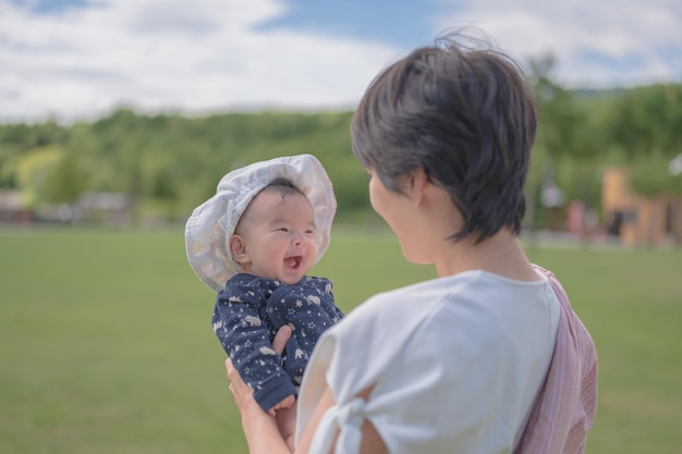 A mother holds her baby in a park