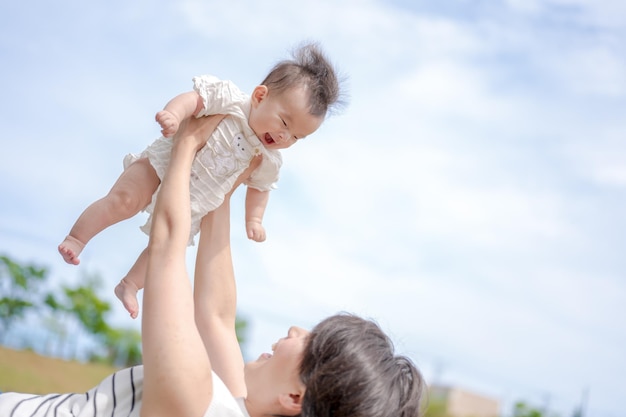 A mother holds her baby up in the air.