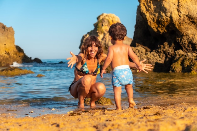 A mother hugging her son on the beach at Praia dos Arrifes Algarve beach Albufeira Portugal