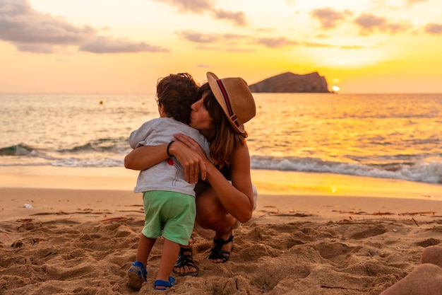 Mother hugging her son at sunset in Cala Comte beach on the island of Ibiza Balearic