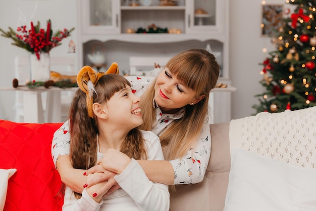 Mother hugs daughter from behind. mom and daughter hug while sitting on the couch.