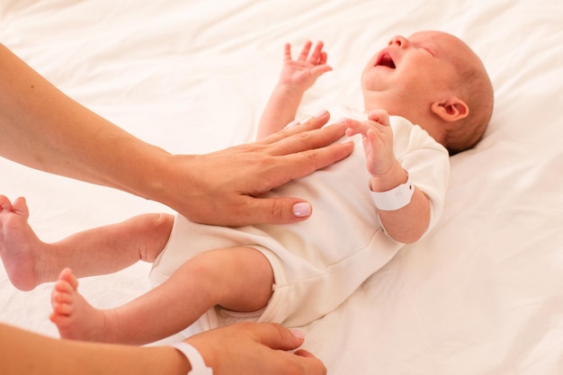 Mother is doing belly massage for newborn