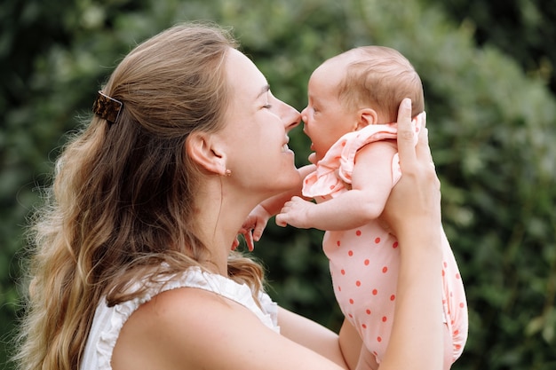 Mother is playing with her baby girl outdoors on summer day