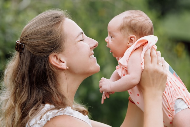 Mother is playing with her baby girl outdoors on summer day