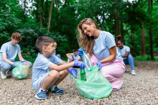 Mother and kids are picking up the garbage to clean up the forest