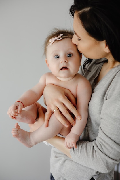 A mother kisses her baby girl in her arms.