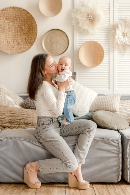 Mother kissing her baby sitting on sofa