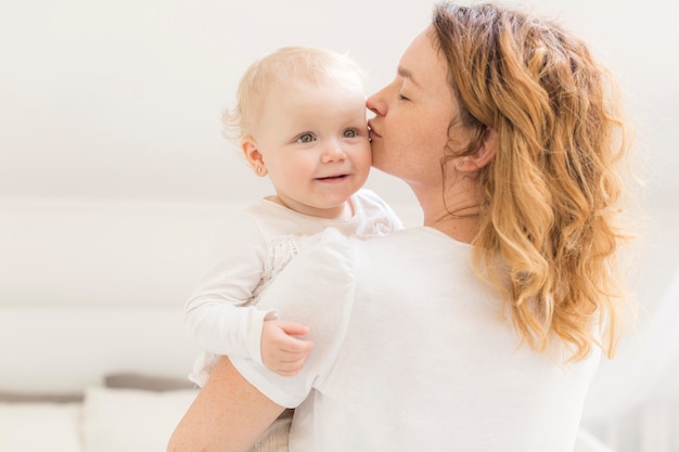 Mother kissing her cute baby girl