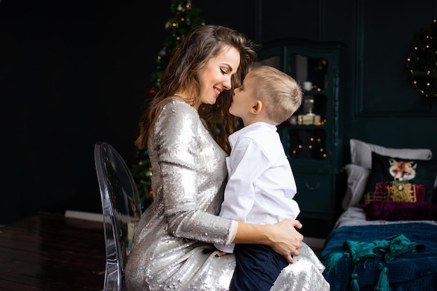 Mother kissing her little son near Christmas tree Christmas New Year winter and holidays seasons concept Family