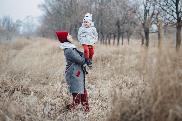 Mother and little baby daughter walking together and having fun in autumn nature background