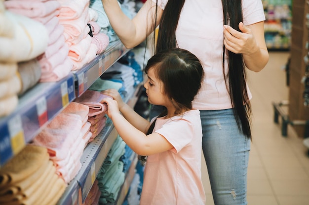 Mother and little daughter buy towels in the supermarket