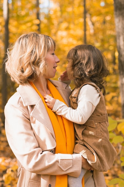 Mother and little daughter enjoying nice autumn day in a park Season family and children concept