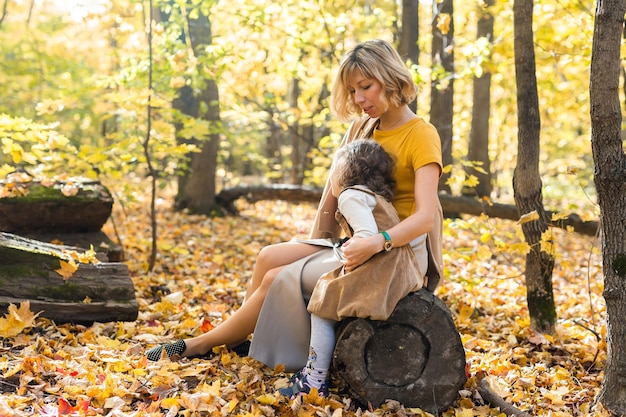 Mother and little daughter enjoying nice autumn day in a park Season family and children concept