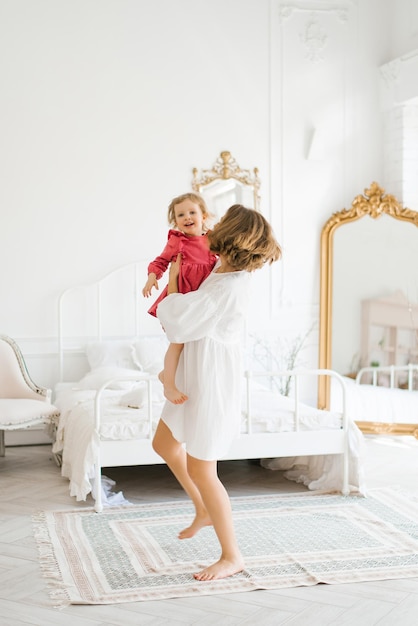 Mother and little daughter have fun in the bright living room of the house