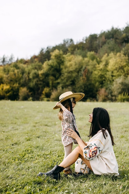 Mother and little daughter spending time together Little girl putting on mother039s big straw hat