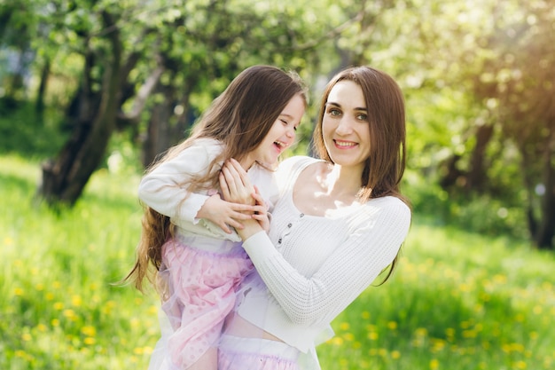 Mother and a little daughter walk in the spring blooming Apple