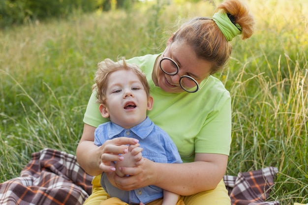 A mother and a little disabled boy hug and play in nature. Disability. Infantile paralysis. Mother's love. Happy childhood.