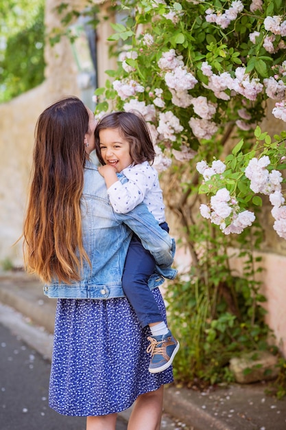 Mother and little handsome baby boy looking at bush with white roses