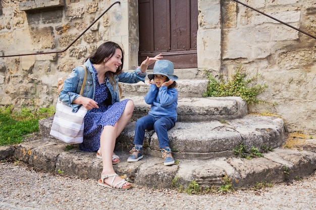 Mother and little handsome baby boy sitting on ancient stone stairs