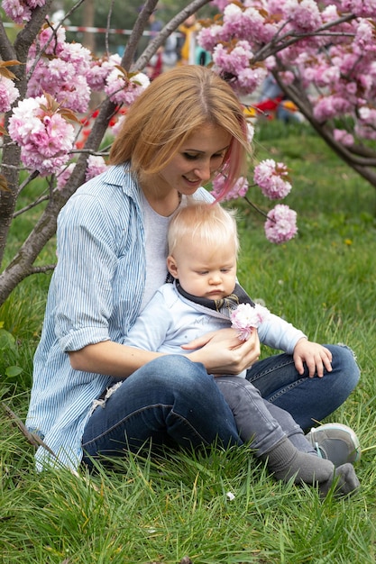 Mother and little son in nature playing at spring park Little boy and mother have a good time on weekend activity in the blooming Sakura gardens