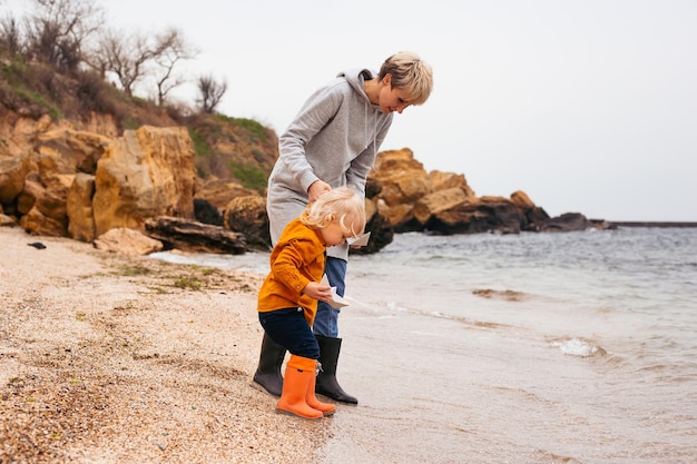 Mother and little son spend time outdoors in the summer or autumn together sitting on beachYoung mother plays with her baby on the promenade Summer vacation for two by the sea