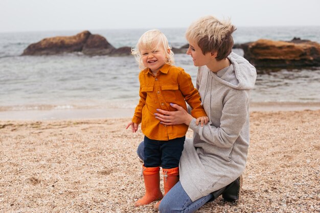 Mother and little son spend time outdoors in the summer or autumn together sitting on beachYoung mother plays with her baby on the promenade Summer vacation for two by the sea