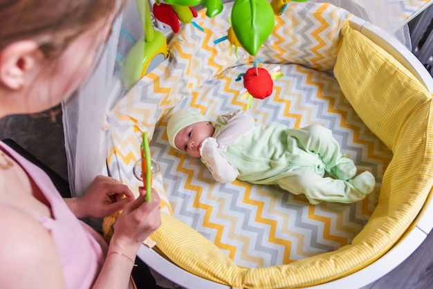 a mother looks at her newborn baby who is lying in a crib