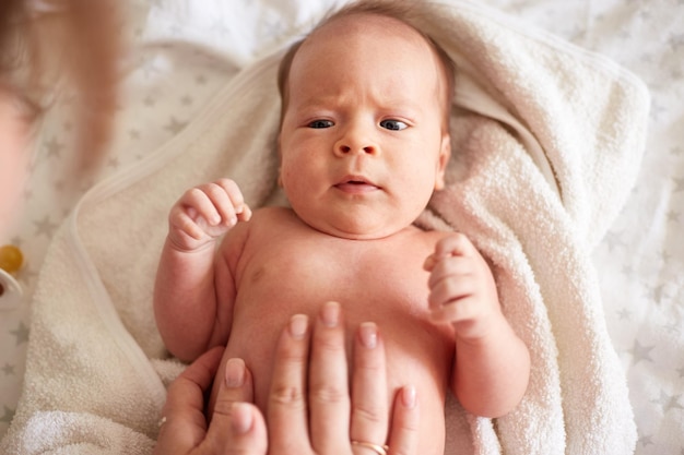 Mother Massaging Her newborn baby boy Realistic home portrait