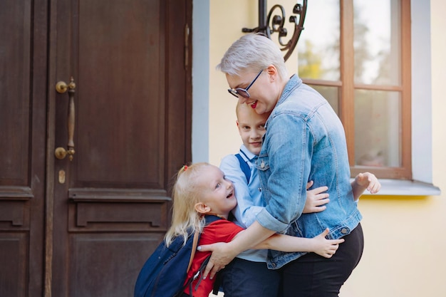 Mother meets children from school Caucasian boy and girl running towards mom hugging her