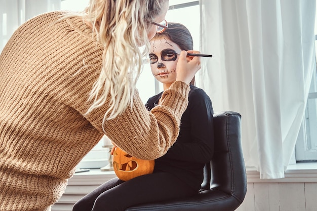 Mother painting daughter face for Halloween party.