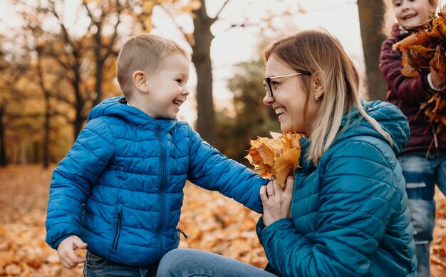 mother playing with her kids with leaves